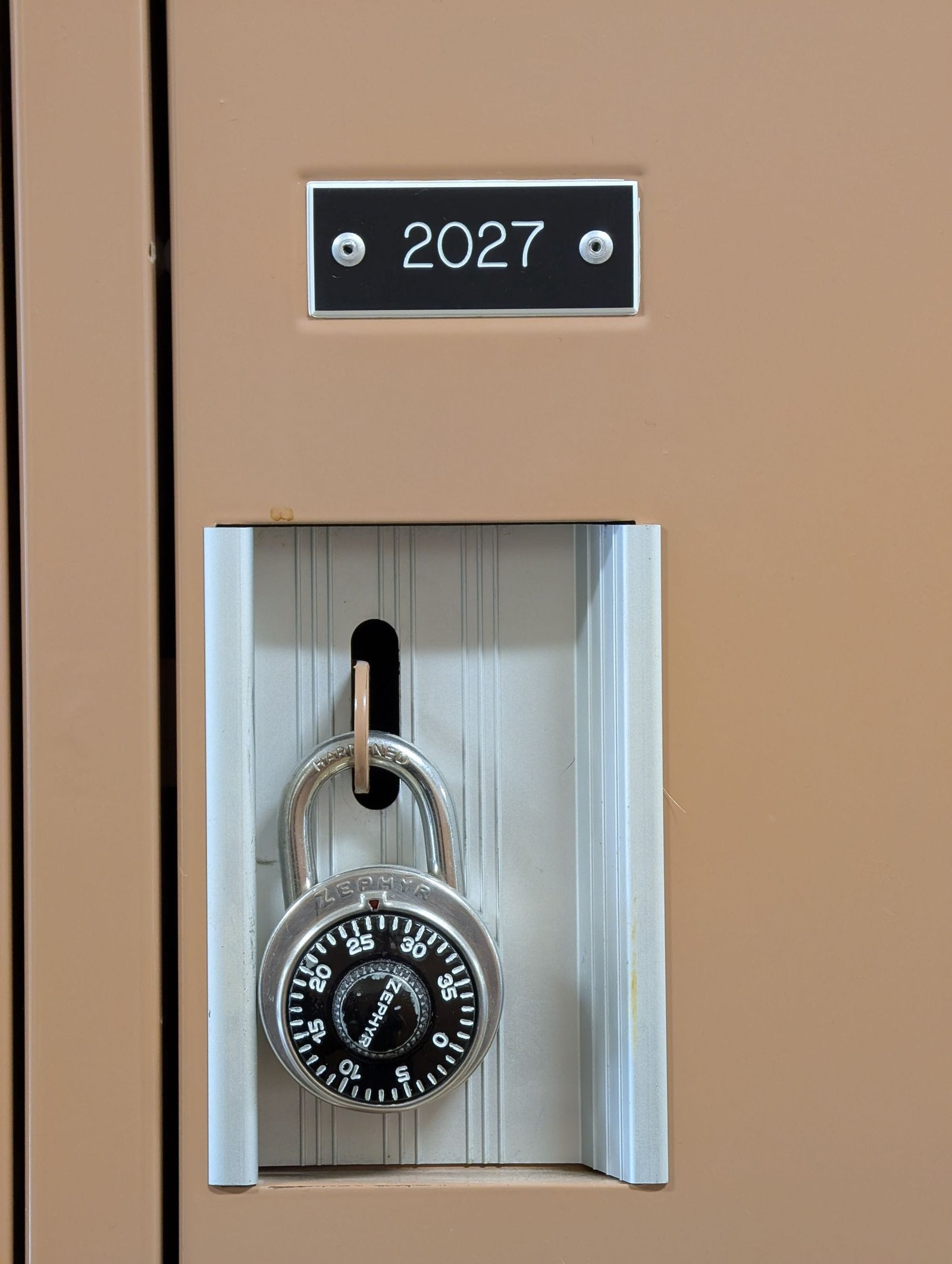 Close-up of a secure locker with a combination lock labeled 2027 indoors.